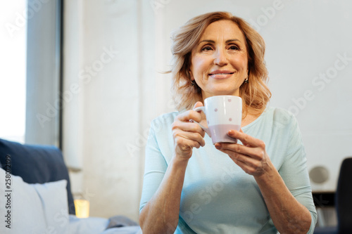Smiling short-haired mature lady being happy with her peaceful morning