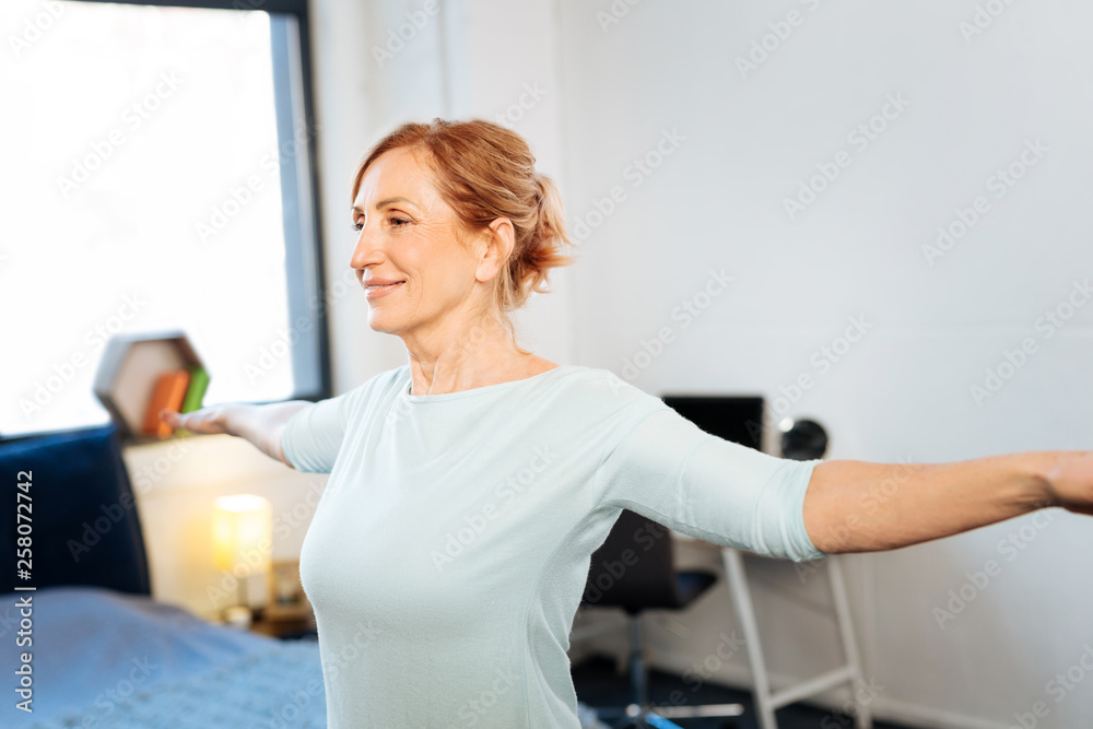 Beaming mature woman with tied hair having workout morning session