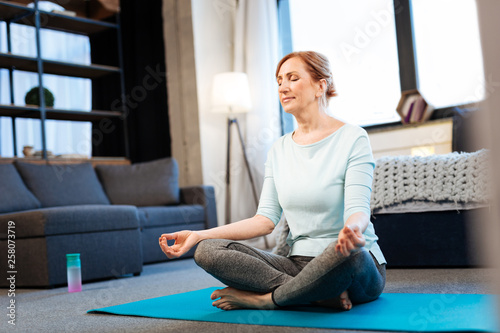 Tranquil good-looking woman meditating with closed eyes