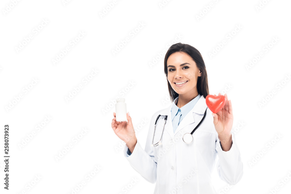 Doctor in white coat with stethoscope holding pills and plastic heart isolated on white Doctor in white coat with stethoscope holding pills and plastic heart isolated on white