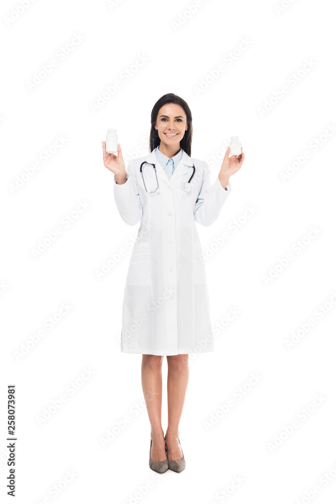Full length view of doctor in white coat with stethoscope holding pills isolated on white Full length view of doctor in white coat with stethoscope holding pills isolated on white