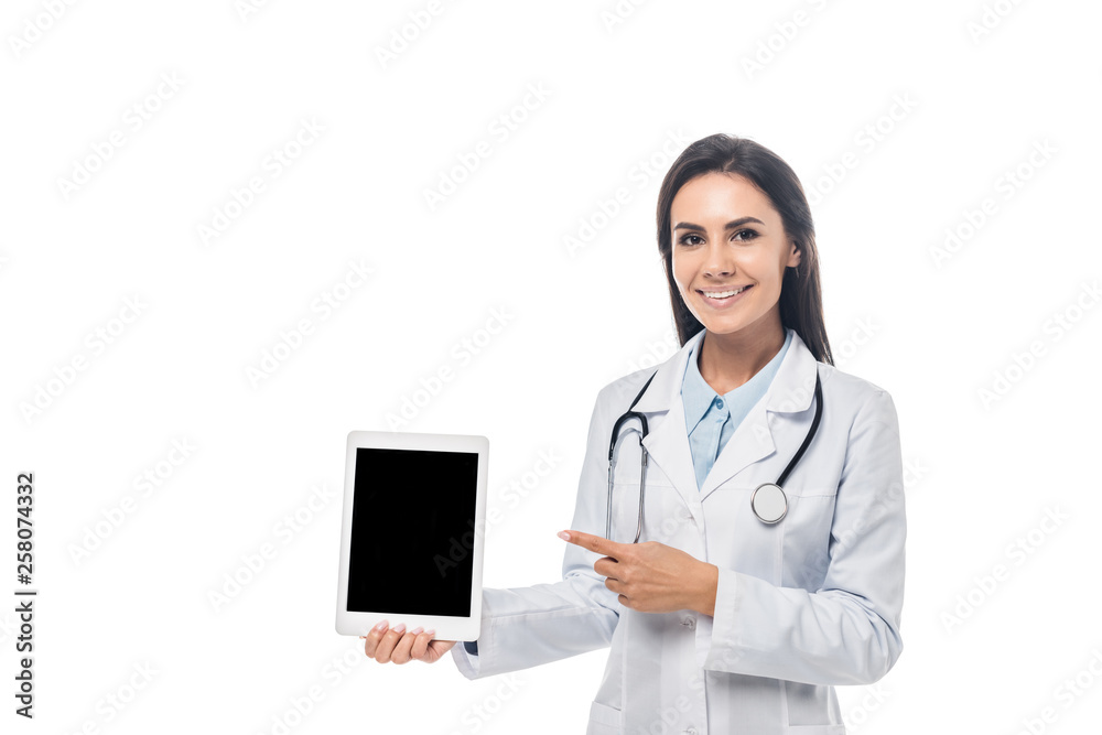 Smiling doctor with stethoscope pointing with finger at digital tablet with blank screen isolated on white