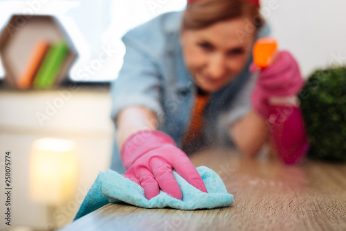 Obraz na plátně Resolute accurate hard-working woman wiping dust from wooden table