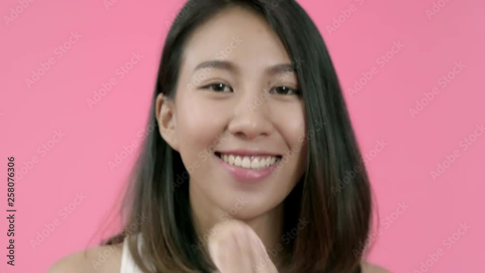Young beautiful fashionable Asian woman applying powder makeup with cosmetic brush in casual clothing over pink background studio shot. Happy smiling adorable glad woman rejoices success. Young beautiful fashionable Asian woman applying powder makeup with cosmetic brush in casual clothing over pink background studio shot. Happy smiling adorable glad woman rejoices success.
