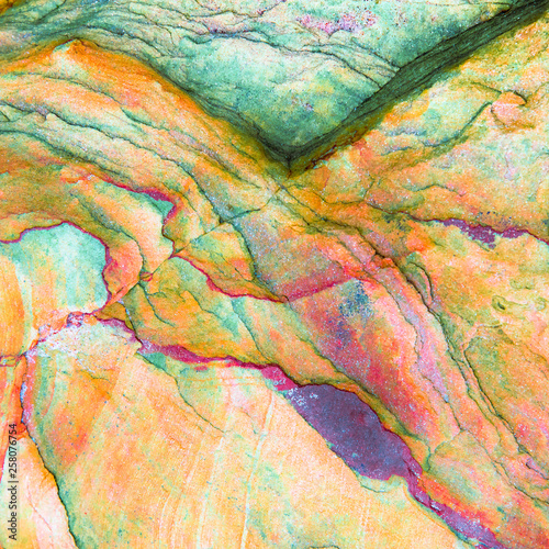 Multicolored rock wall from bottom sediments red orange dark rays crack smooth