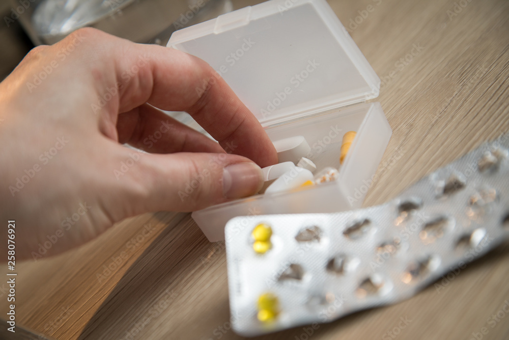 Frau nimmt gelbe Pillen Tabletten aus Blister und Pillendose mit Wasser Glas  auf Holz Nachttisch Stock Photo | Adobe Stock