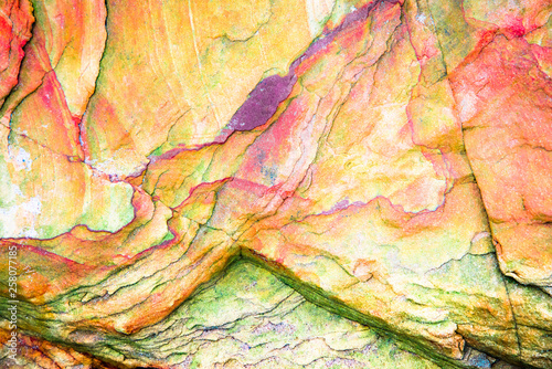 Multicolored rock wall from bottom sediments red orange dark rays crack smooth