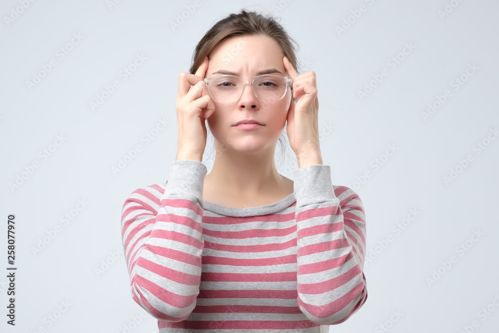 Woman keeps fingers on temples. migraine concept Woman keeps fingers on temples. migraine concept