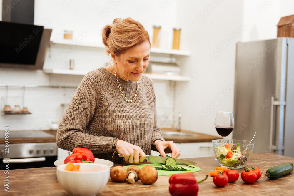 Concentrated mature woman getting dinner ready on wooden table Concentrated mature woman getting dinner ready on wooden table
