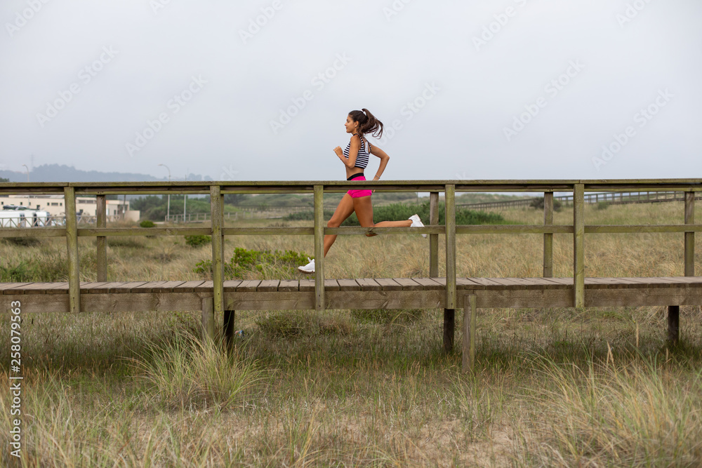 Young female runner training. Summer running outdoor workout. Fitness lifestyle and exercising. San Juan de Nieva, Asturias, Spain.