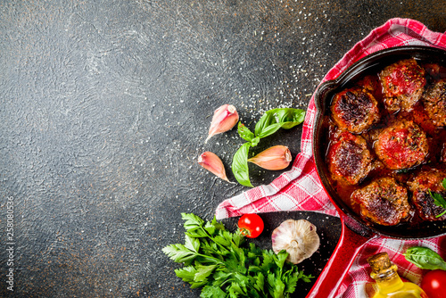 Homemade baked meatballs with tomato sauce in small frying pan on dark rusty stone table. Top view copy space