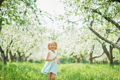 girl sniffing flowers of apple orchard. garden with flowering trees