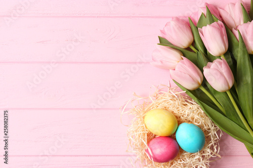 easter composition. Easter eggs and flowers on wooden color background top view. flatlay