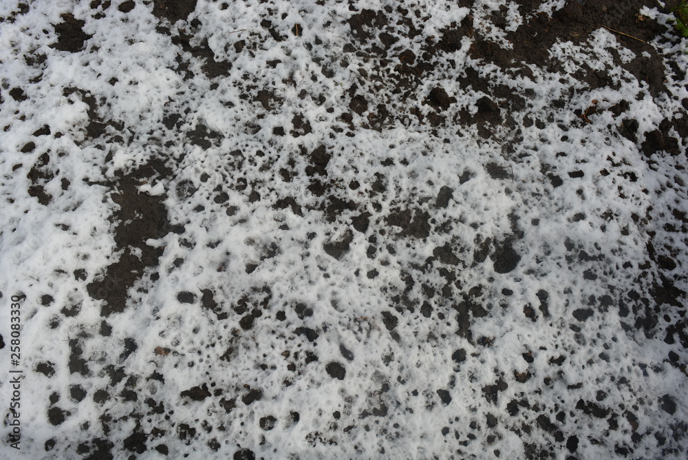 Black earth with melting white snow, spring time period