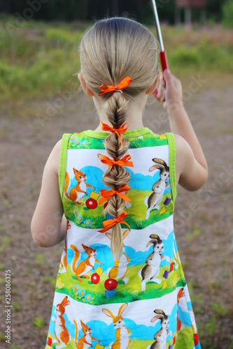 A little girl with braided hair standing under an umbrella