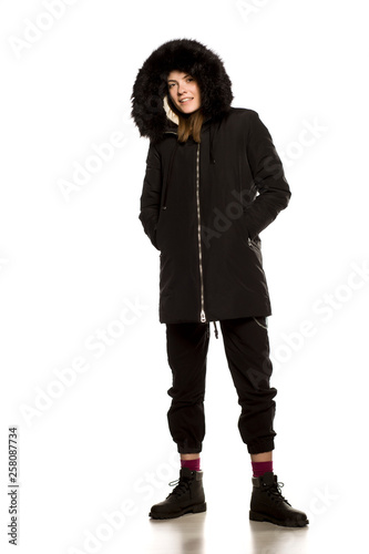 Young model in winter jacket with hood posing on white background
