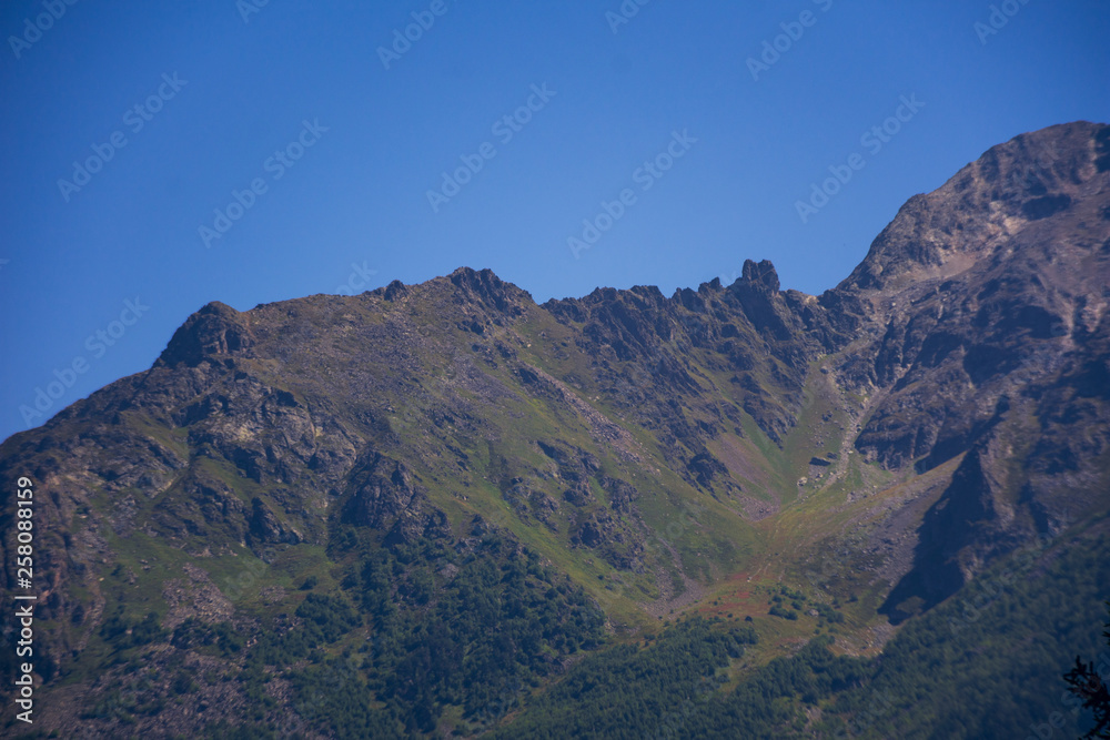 A huge panorama of high Caucasus mountains and beautiful trees on a sunny summer day. A very large amount of stones. A huge panorama of high Caucasus mountains and beautiful trees on a sunny summer day. A very large amount of stones.