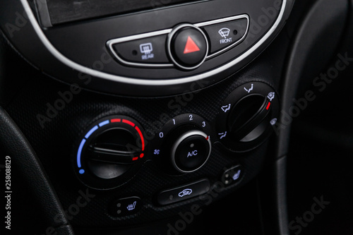 Сlose-up of the car black interior: dashboard, adjustment of the blower, air conditioner, player, accelerator handle and other buttons.