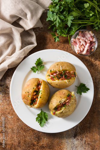 Stuffed potatoes with bacon and cheese on plate on rusty background