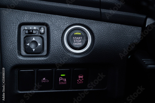 Сlose-up of the car  grey interior: start stop engine button,side mirror adjustment buttons, parking systems and other buttons . © Виталий Сова