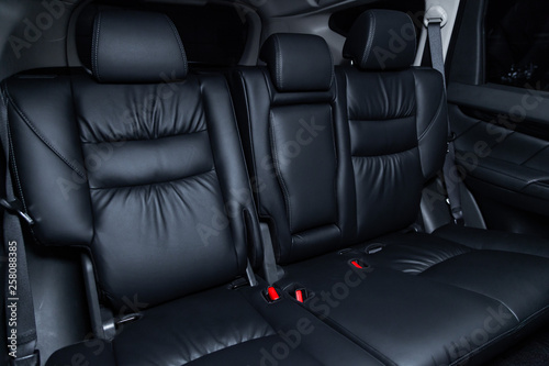 Сlose-up of the car black interior: black leather rear seats and seat belts .