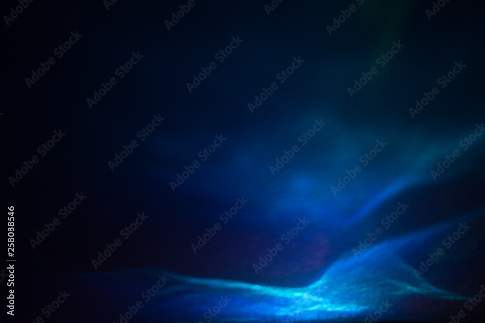 Abstract light waves with glitter effect. Shiny blurry blue lines on dark background. Defocused soft lens flare glow.