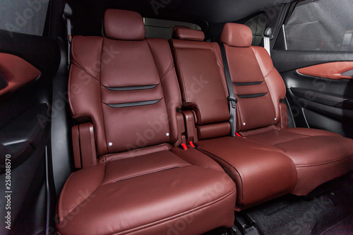 Сlose-up of the car modern interior: red leather rear seats and seat belts .