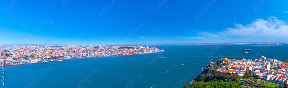 Summertime sunshine day panoramic cityscape view of Almada and Lisbon, Tagus river, Portugal.