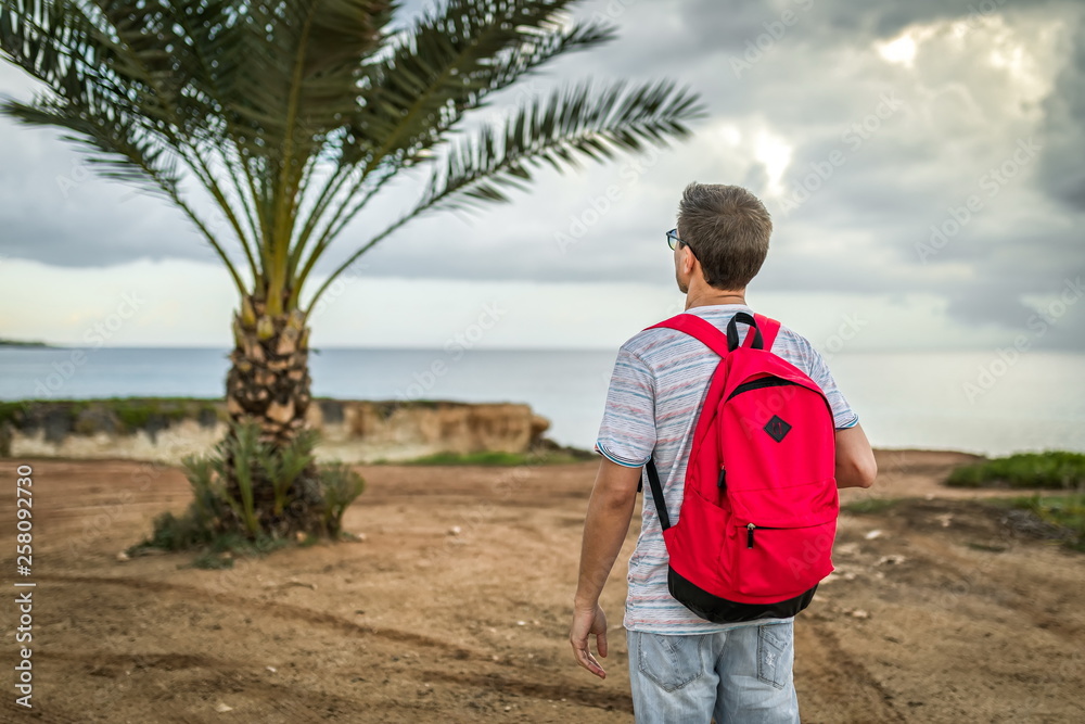 man traveler with backpack on palm outside or outdoor summer adventure trip