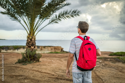 Obraz na płótnie man traveler with backpack on palm outside or outdoor summer adventure trip w salonie