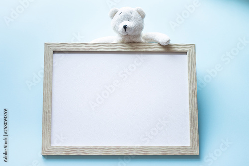 Teddy bear and wood photo frame on blue background. frame for kids. birthday concept