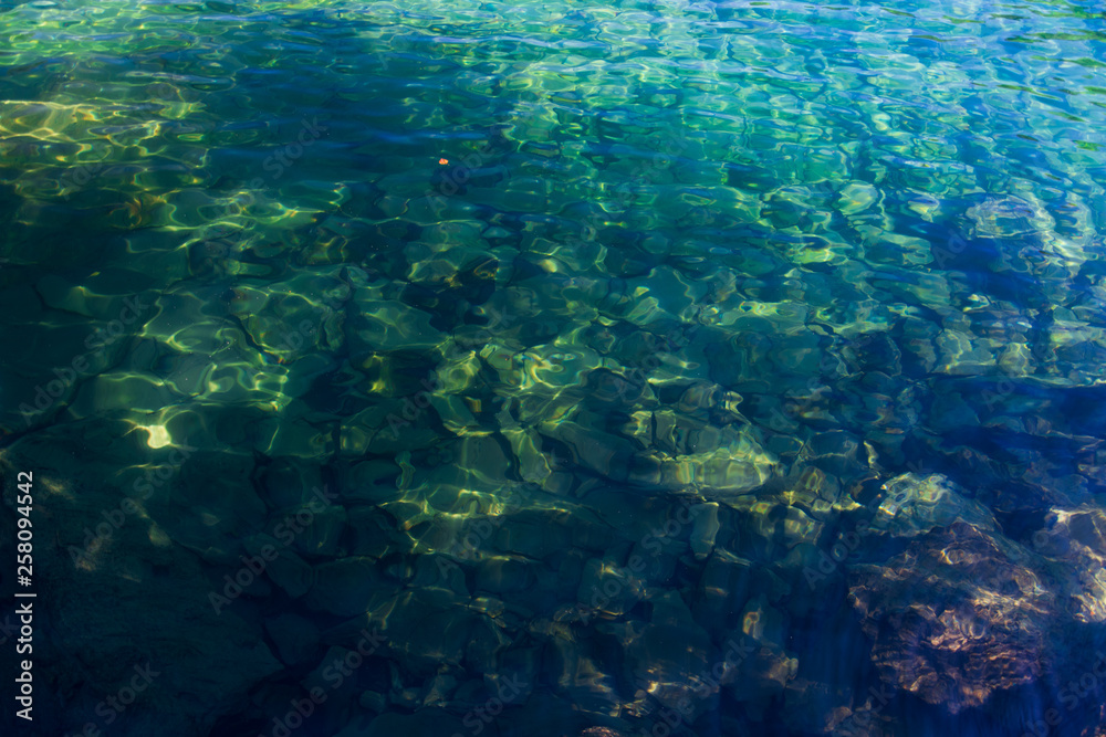 Crystal-clear water in the high-mountainous lake of Baduk with stones at the bottom on a summer day.