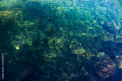 Crystal-clear water in the high-mountainous lake of Baduk with stones at the bottom on a summer day.