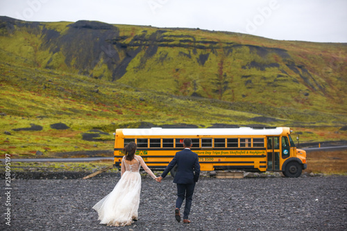 Beautiful wedding couple posing with yellow school bus
