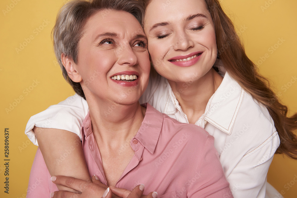 Close up of beautiful woman with her charming daughter posing for camera Close up of beautiful woman with her charming daughter posing for camera