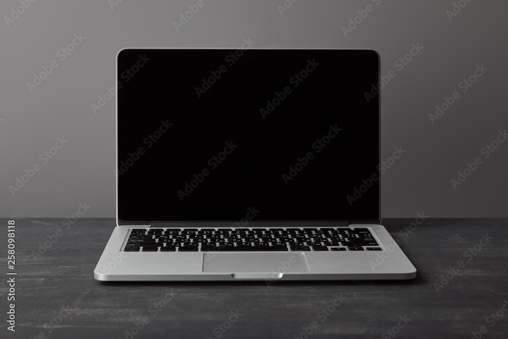 Laptop with blank screen on dark textured surface on grey Laptop with blank screen on dark textured surface on grey