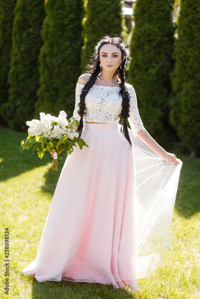 portrait of a black-haired bridesmaid in a pink dress on the street