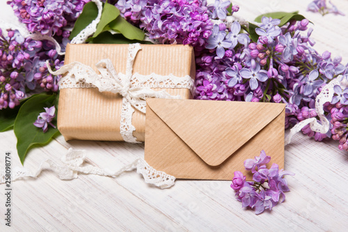 Lilac flowres, gift box and envelope on white wooden background. Retro style. Holiday composition, copy space