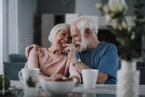 Positive elder couple drinking tea with cookies