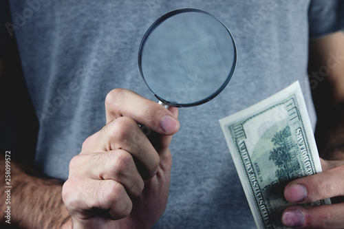 man holding magnifying glass and money.
