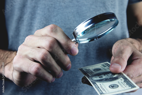 man holding magnifying glass and money.