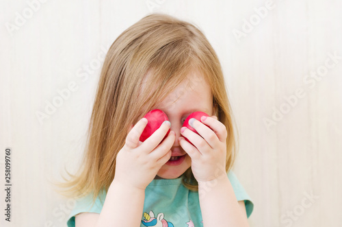 little girl hiding behind easter eggs