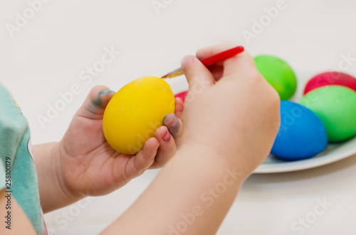 the child paints yellow easter egg