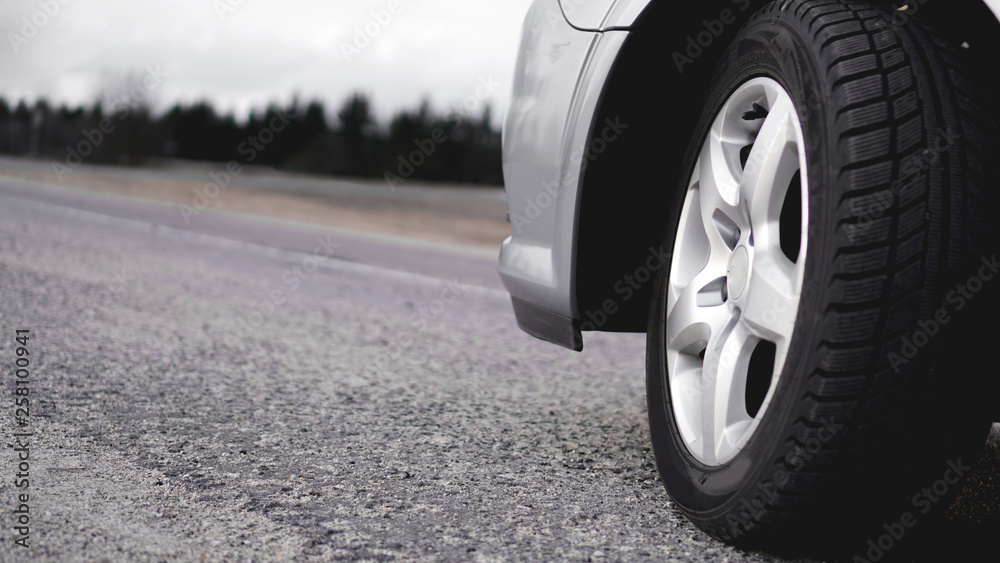 Close up of Wheel of silver car on the road. Photo in gray tones
