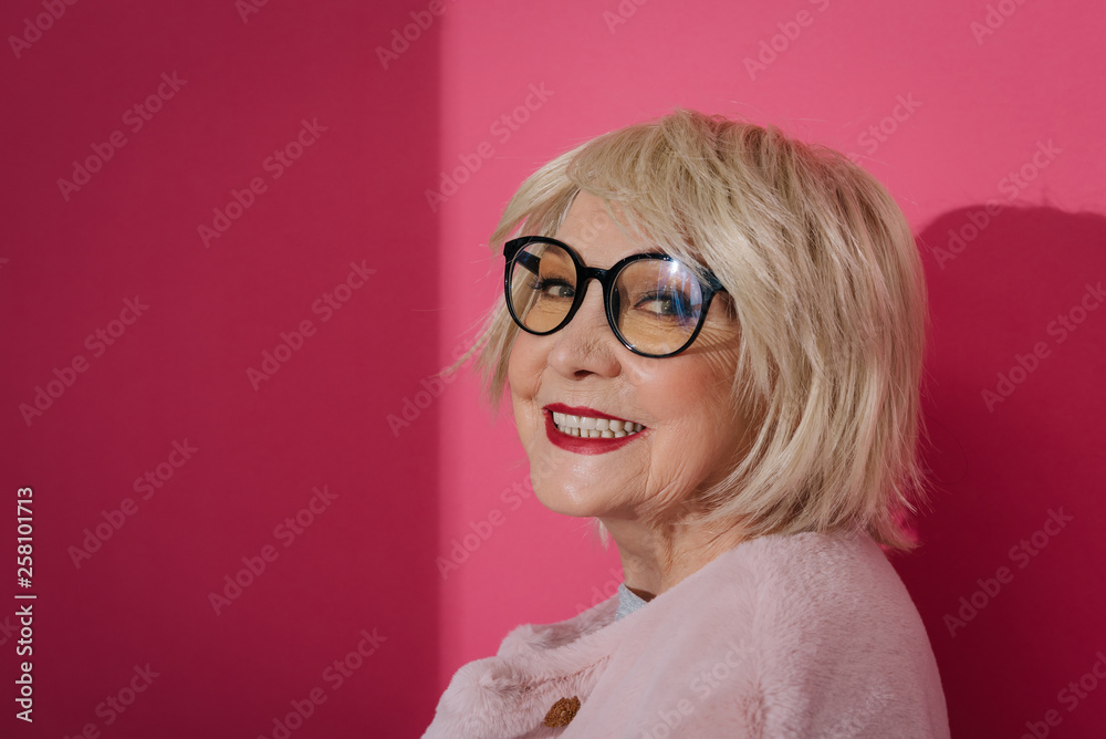 Portrait of fashionable happy elderly woman in eyeglasses looking at camera