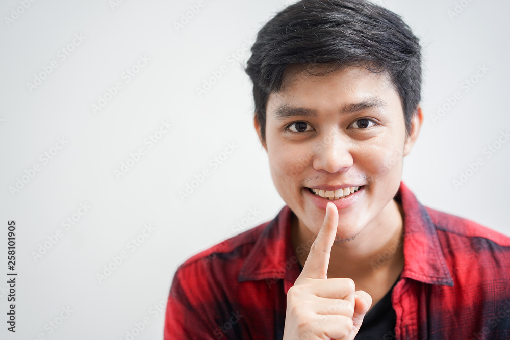 close up young asian man use finger on lip for april fools day and sign language concept