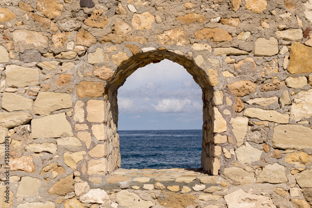 The texture of the stone wall close-up with window and sea view