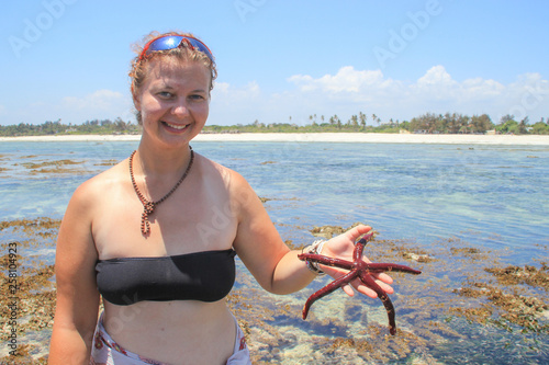 Plump white girl in a bathing suit holding a red starfish. Bodipositive girl photo
