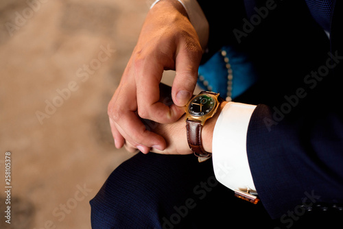 Male businessman dresses and adjusts his watch, preparing for a meeting. Clock