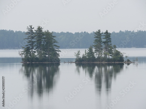 Beautiful view of Damariscotta Lake in Maine on a calm day with two islands that have stacked stones, or cairns, in between them